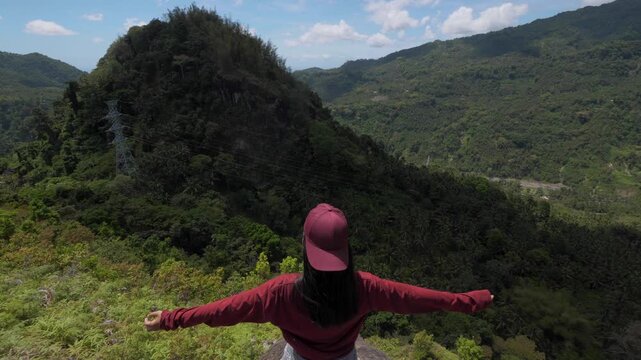 Asian Young Woman Looks At The Mountain and Looks Around in Asia, Travels through the Jungle among Palm Trees in Sunny Weather