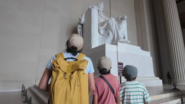 Mother with two children visiting the impressive abraham lincoln statue at the lincoln memorial in washington d.C., a significant american historical landmark