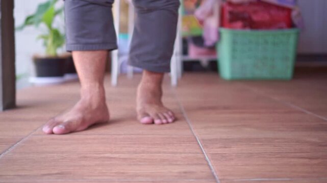 Low-angle view of a broom sweeping a wood-look floor at home. Cleaning footage capturing tidiness, chores, and everyday home maintenance.