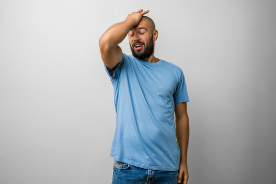 Man caucasian beard young t shirt blue with hand on head after a mistake - error, forgot memory, frustrated studio portrait