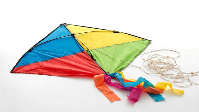 Colorful diamond kite with tail and spool of string on white background