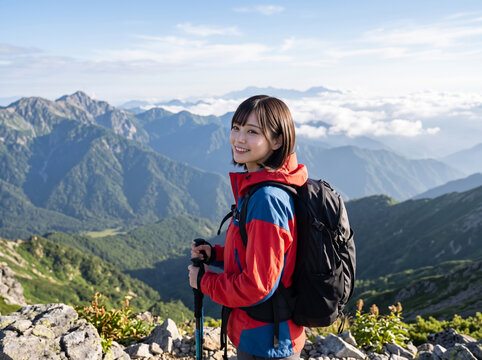 美しい山脈を背に登山ストックを持って笑顔で立つ登山服の女性