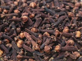Fototapeta premium Close up top view of dried cloves spice background texture. Organic aromatic culinary ingredient, traditional herbal medicine, and natural raw spice for cooking, baking, and flavoring 