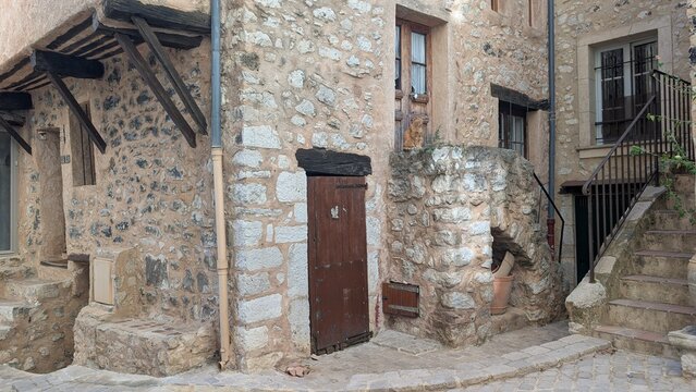 Ginger cat sitting outside a rustic stone house in Tourrettes sur Loup, France. 