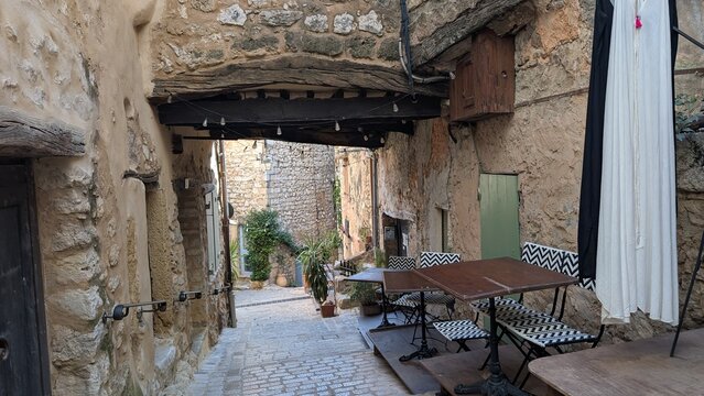 Narrow stone alley with outdoor cafe in Tourrettes-sur-Loup, France. 