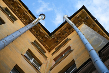 Two metal rain downspout gutters attached to a yellow stucco wall of a classic vintage residential apartment building architecture structure. Old municipal drainage utility system engineering, house.  © Dmitry Presnyakov