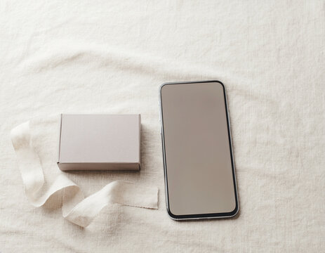 Empty smartphone display and plain box, flat lay ecommerce
