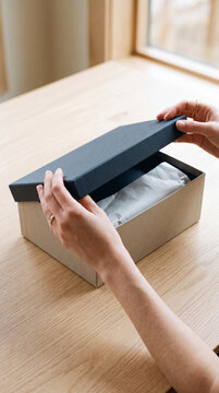 Hands opening a plain box, contents not revealed, copy space