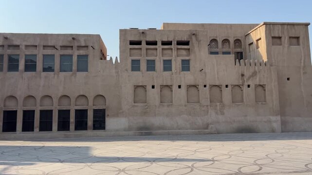 A scenic panoramic view of the beautifully restored historic buildings and sand-colored structures in the Al Seef heritage area along Dubai Creek. 
