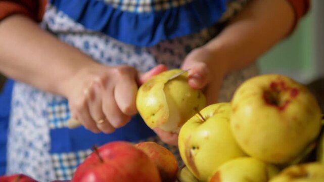 Peeling Fresh Organic Yellow Apple with Kitchen Knife for Home Cooking - Hands Removing Peel from Natural Bio Yellow Fruit Above Heap of Harvested Apples