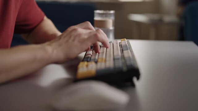 Detailed side view of male hands swiftly typing on custom mechanical keyboard at office desk. Concept of focused effort programmer, gamer, writer working on project, close-up, slow motion.