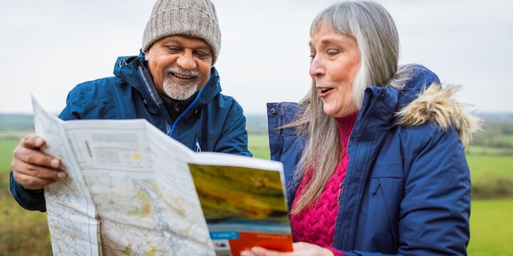 Elderly couple in winter clothing reading a map outdoors.