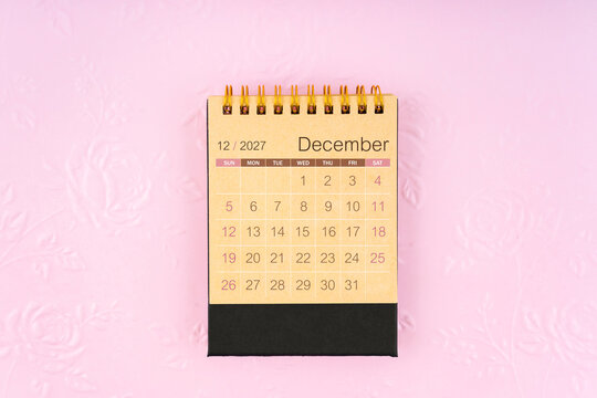 Desk calendar for December 2027 on flower pattern embossed as background.