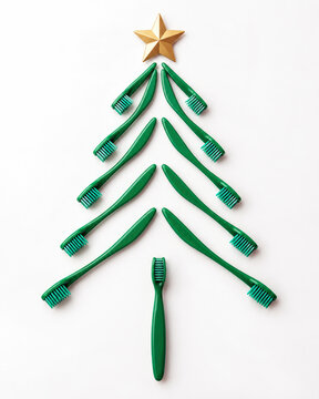 Green toothbrushes arranged as Christmas tree with gold star on white - Christmas dental care and dentist concept