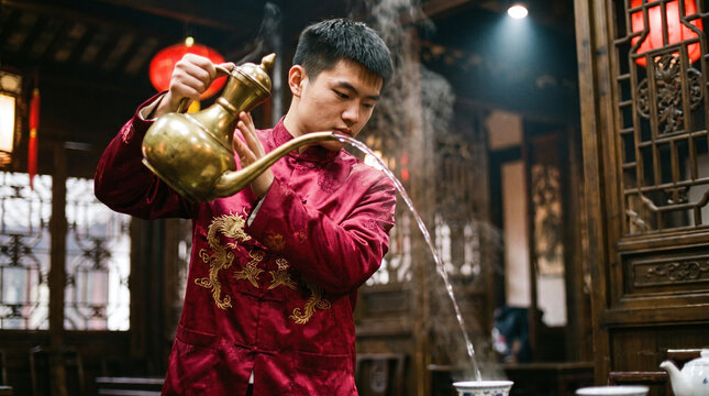 kung fu tea master pouring hot tea from traditional long spouted kettle