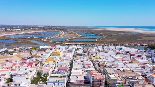 Beautiful aerial perspective flying above the coastal town of fuseta. Revealing its charming architecture. The ria formosa natural park. And the extensive salt evaporation ponds in algarve. Portugal