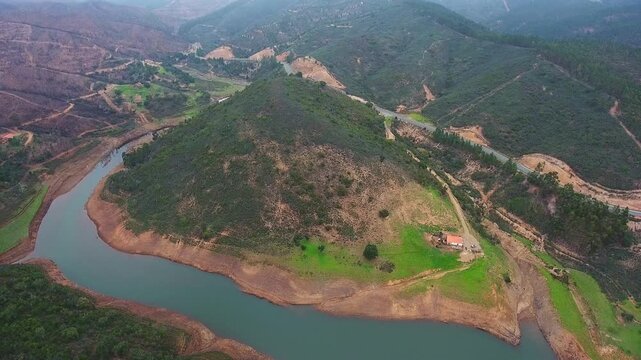Aerial view of the devastating effects of a forest fire, showing a burnt and destroyed landscape next to a winding river in the mountains of monchique, algarve region of portugal