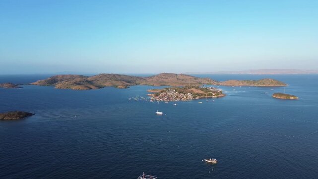 ORBIT DRONE SHOT CIRCLING SMALL FISHING VILLAGE ISLAND IN BIMA, WEST NUSA TENGGARA, INDONESIA WITH BOATS AND BLUE OCEAN