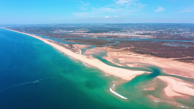Stunning aerial perspective flying over the beautiful sandy coastline of faro beach and deserta island in algarve, portugal, revealing the turquoise ocean and the vast ria formosa natural park