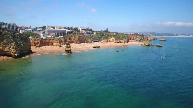 Stunning aerial perspective of praia dona ana, revealing its iconic golden cliffs, sandy beach, and clear turquoise waters of the atlantic ocean, with boats sailing near the shore in algarve