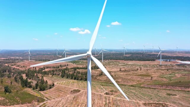 Majestic aerial view of a large wind farm, with white wind turbines rotating to generate clean and sustainable energy under a bright blue sky in the spanish countryside during a sunny day