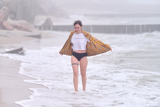 Young woman walking through foggy sea surf along coastal beach