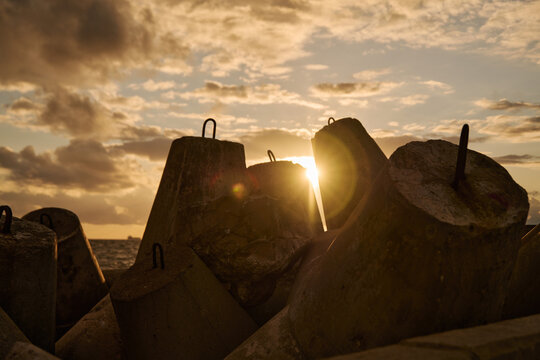 Concrete wave breakers guarding coastline beneath golden sunset light