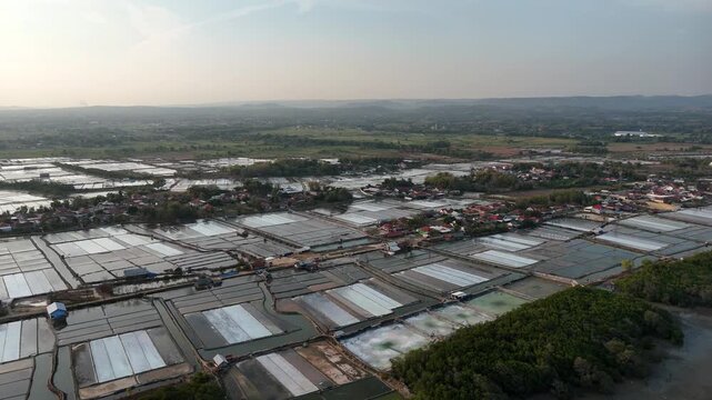 Aerial view of traditional salt pans and coastal village surrounded by agricultural landscape