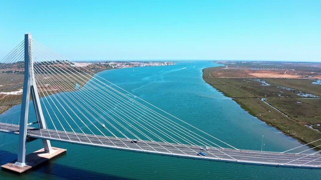 Aerial view of the cable stayed guadiana international bridge spanning the river between ayamonte, spain, and vila real de santo antonio, portugal, under a clear blue sky on a sunny day