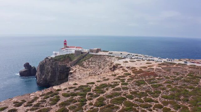 Dramatic aerial perspective of the historic lighthouse at cape st. Vincent in sagres, portugal, standing majestically on rugged cliffs above the deep blue atlantic ocean on a sunny day