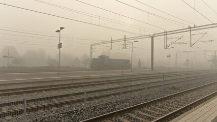 Locomotive standing on railway tracks at a foggy station © Oddette