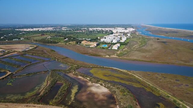 Stunning aerial perspective flying over the picturesque coastal town of cabanas de tavira, revealing the beautiful salt pans, ria formosa estuary, and the vast atlantic ocean shoreline