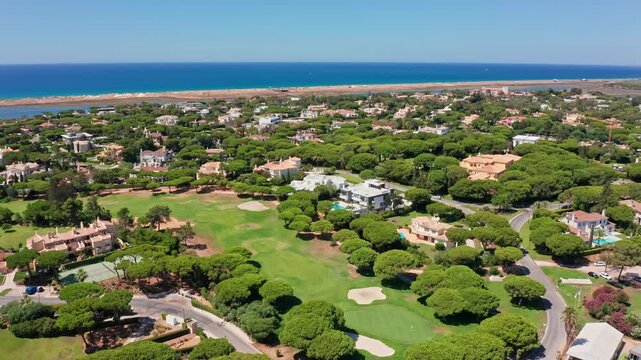 Picturesque aerial view revealing the luxurious coastal resort of vale de lobo in the algarve region of southern portugal. Featuring a pristine golf course surrounded by elegant villas and pine trees