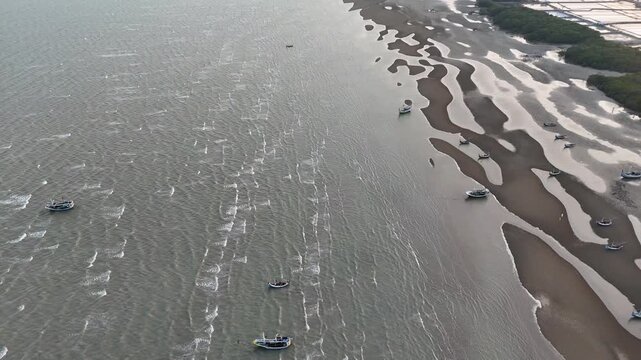 Aerial view of many boats navigating through shallow water with sandbars visible