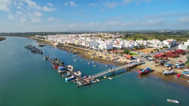 Panoramic aerial footage showing the picturesque fishing village of santa luzia. Known as the octopus capital. With its whitewashed houses and boats moored along the gilao river in algarve. Portugal