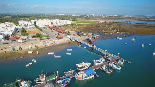 Beautiful aerial view of santa luzia, algarve fishing village with colorful boats moored at the pier, tranquil ria formosa wetlands and sunlit coastal houses and marina