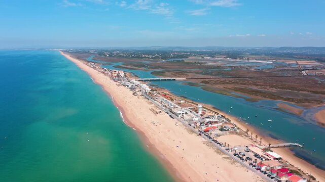 Spectacular aerial perspective flying along faro beach, a stunning sandbar separating the vibrant atlantic ocean from the tranquil ria formosa lagoon in the beautiful algarve region of portugal