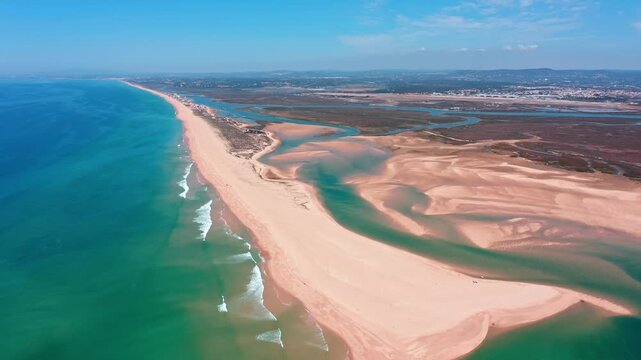 Spectacular aerial perspective flying over the pristine sandy beaches of ilha deserta and the intricate waterways of the ria formosa lagoon system, showcasing a unique coastal landscape