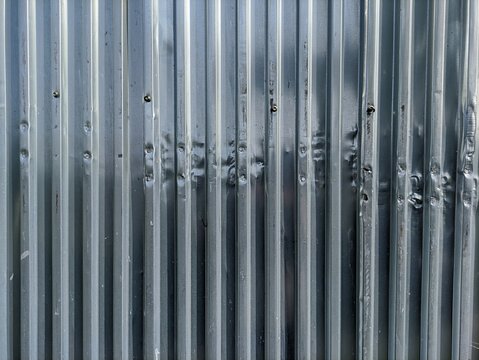 Corrugated metal zinc sheet texture background with vertical lines and dented surface. Perfect for background, industrial, construction, architectural design, and rustic material texture concepts.
