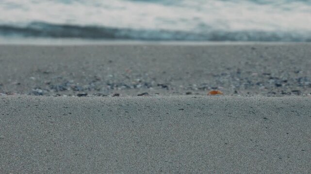 Wide Light Gray Sandy Beach with Waves Rolling Ashore in the Background