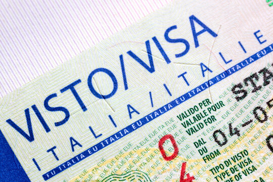 Macro details of Italian Schengen visa sticker page inside passport. Blue printed text elements, security microprint lines, stamp details on official international European travel document.