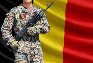 Fototapeta premium Belgium flag with soldier in military uniform holding assault rifle in front of it