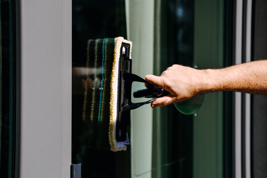 Hand applies microfiber washer to window glass. Window washer applicator, wetting glass, first step, loosening dirt