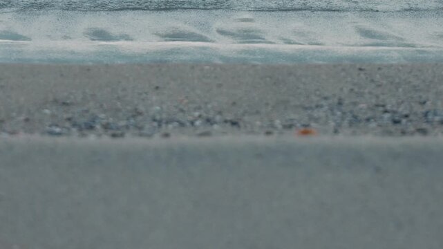 Wide Light Gray Sandy Beach with Waves Rolling Ashore in the Background