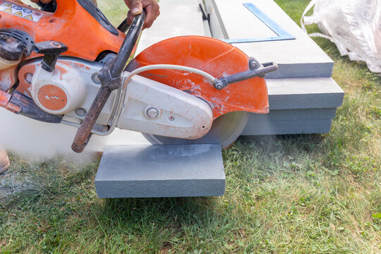 closeup of construction worker cutting bluestone with a gas powered masonry circular saw