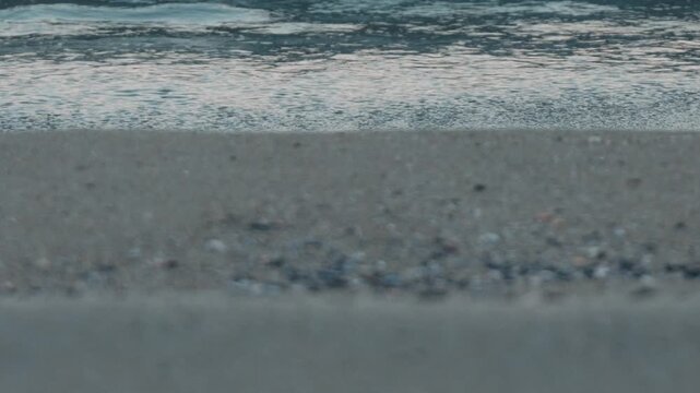 Wide Light Gray Sandy Beach with Waves Rolling Ashore in the Background