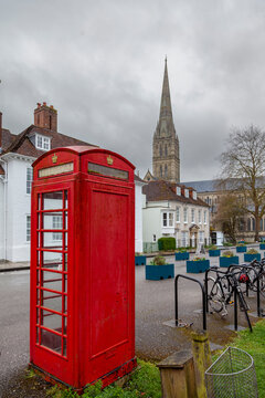 Red k6 telephone box standing in a square with salisbury cathedral spire in the background