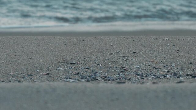 Wide Light Gray Sandy Beach with Waves Rolling Ashore in the Background