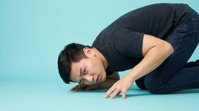 Young Asian man checking floor level with one eye closed.