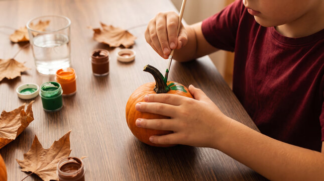 Halloween pumpkin painted by hand with child creating colorful autumn craft. Happy autumn holiday celebration party. cute creative drawing craft, fun orange colours decoration